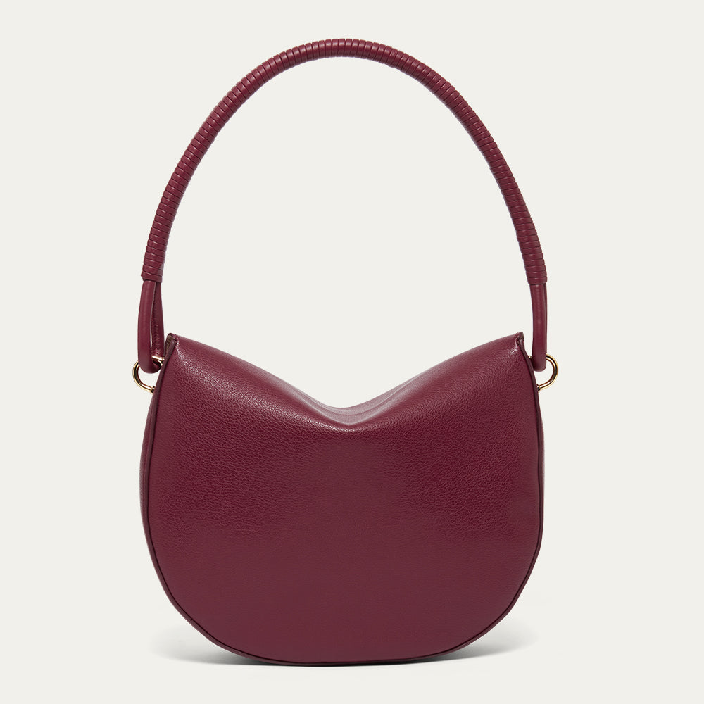 Burgundy leather shoulder bag with a corded handle on a light gray background