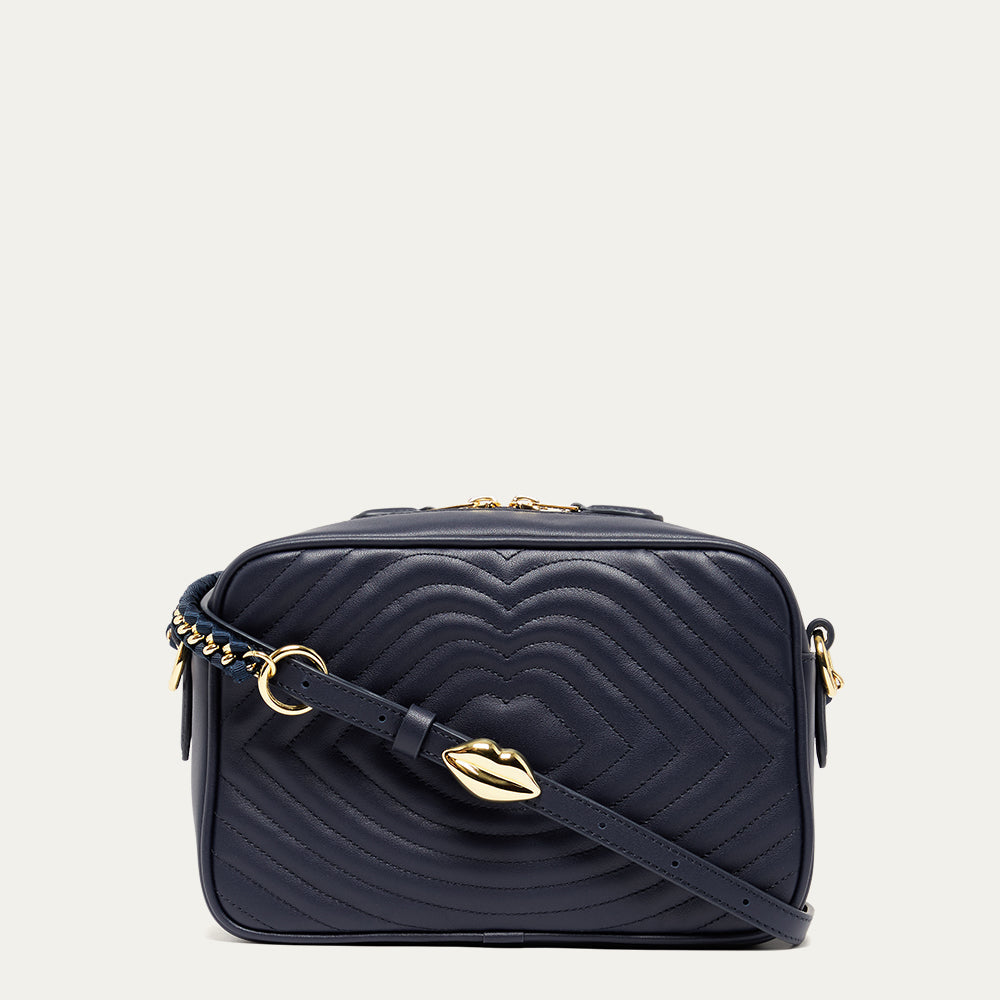 Navy blue leather quilted handbag with gold accents on a light grey background