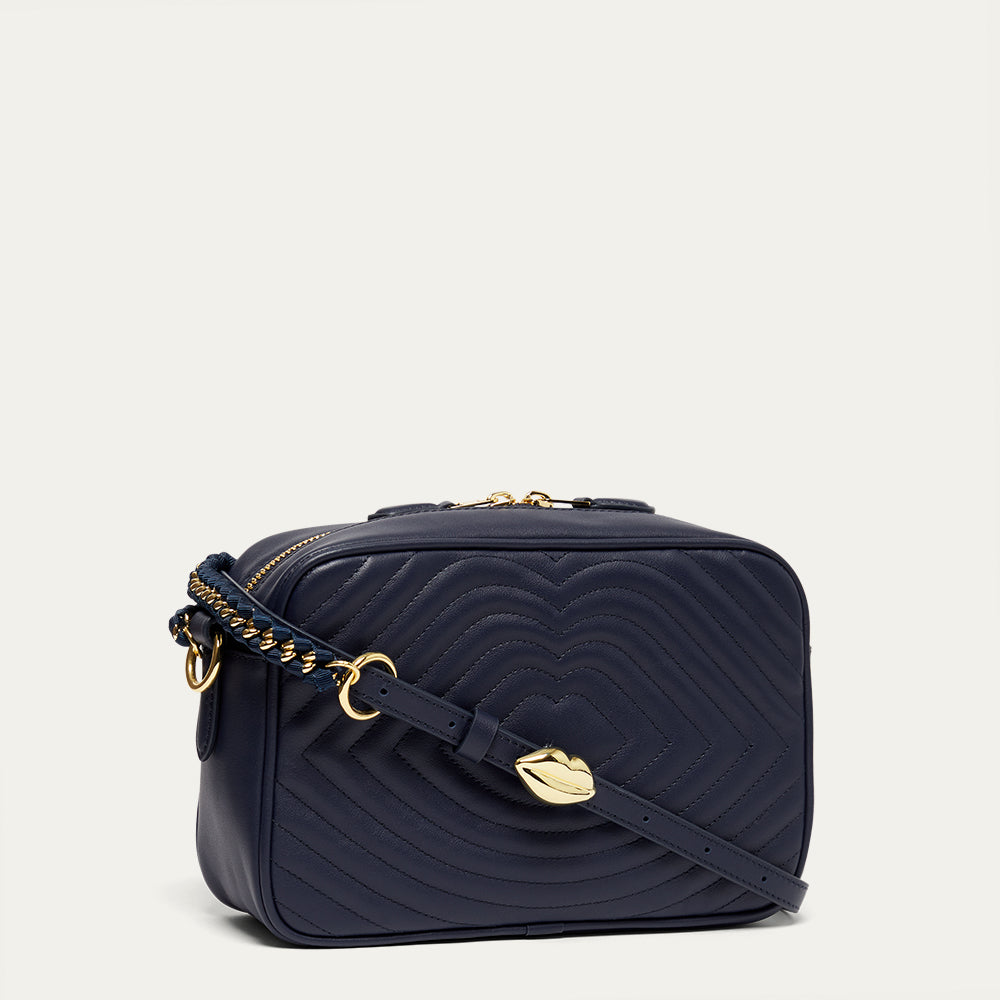 Navy blue leather quilted handbag with gold accents on a light grey background
