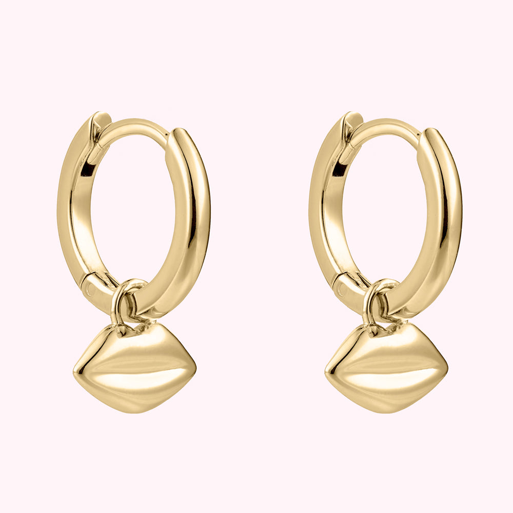 Angled image of a pair or gold plated sterling silver hoop earrings with lip charms.