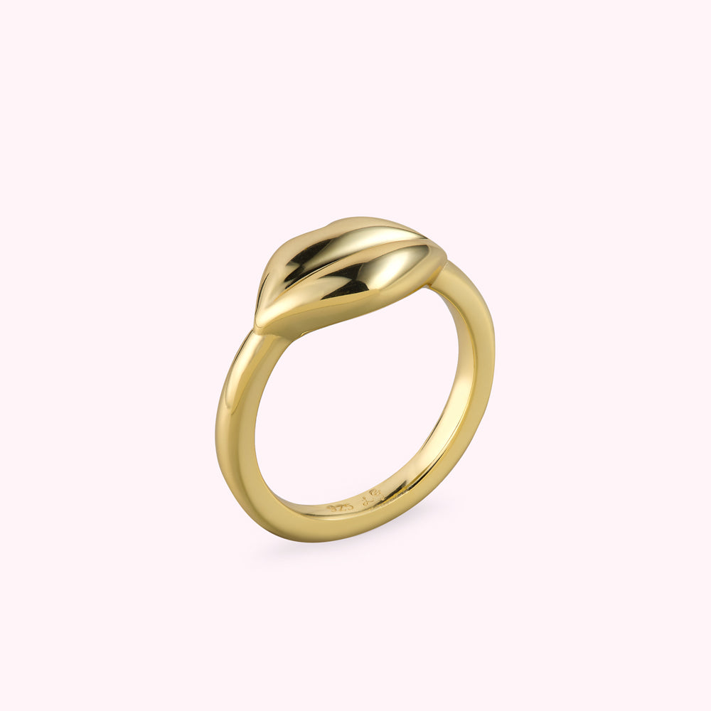 Angle side image of a gold lip shaped ring on a white background.