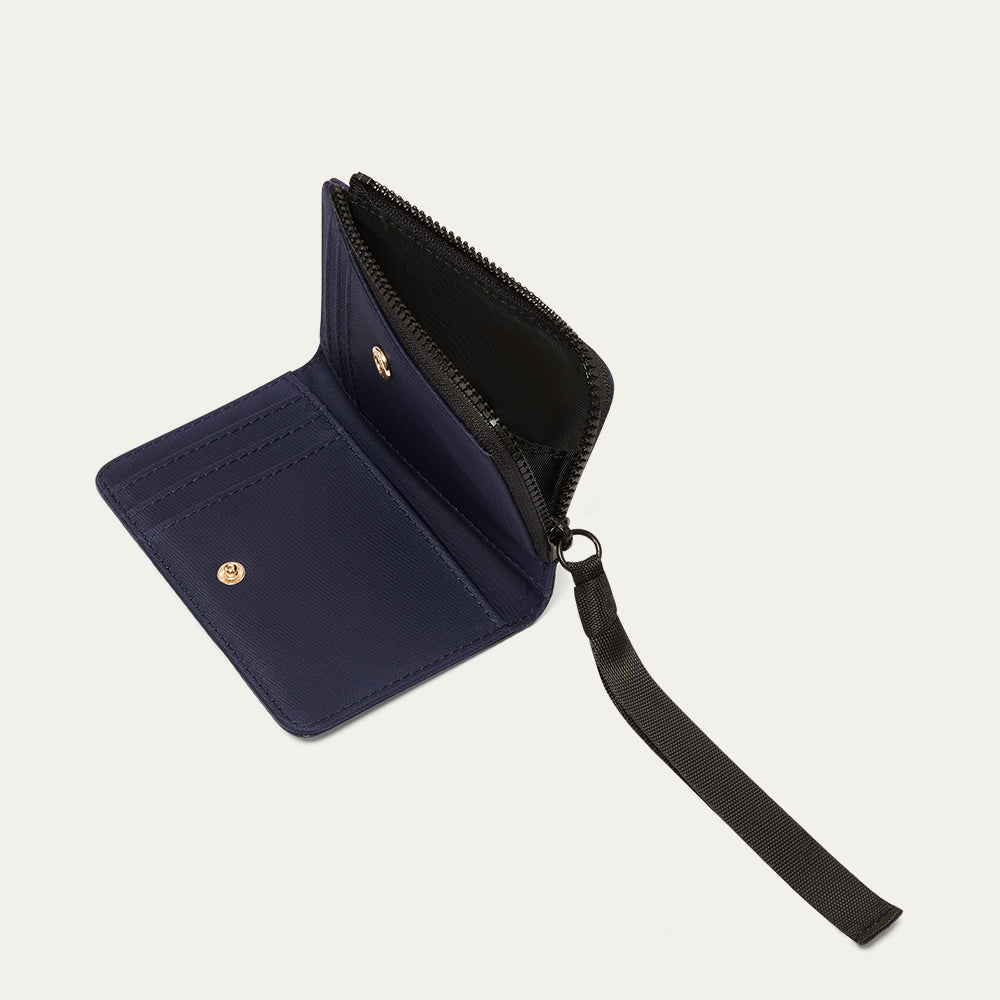 Navy blue wallet with a black ribbon zip pull open on a light gray background