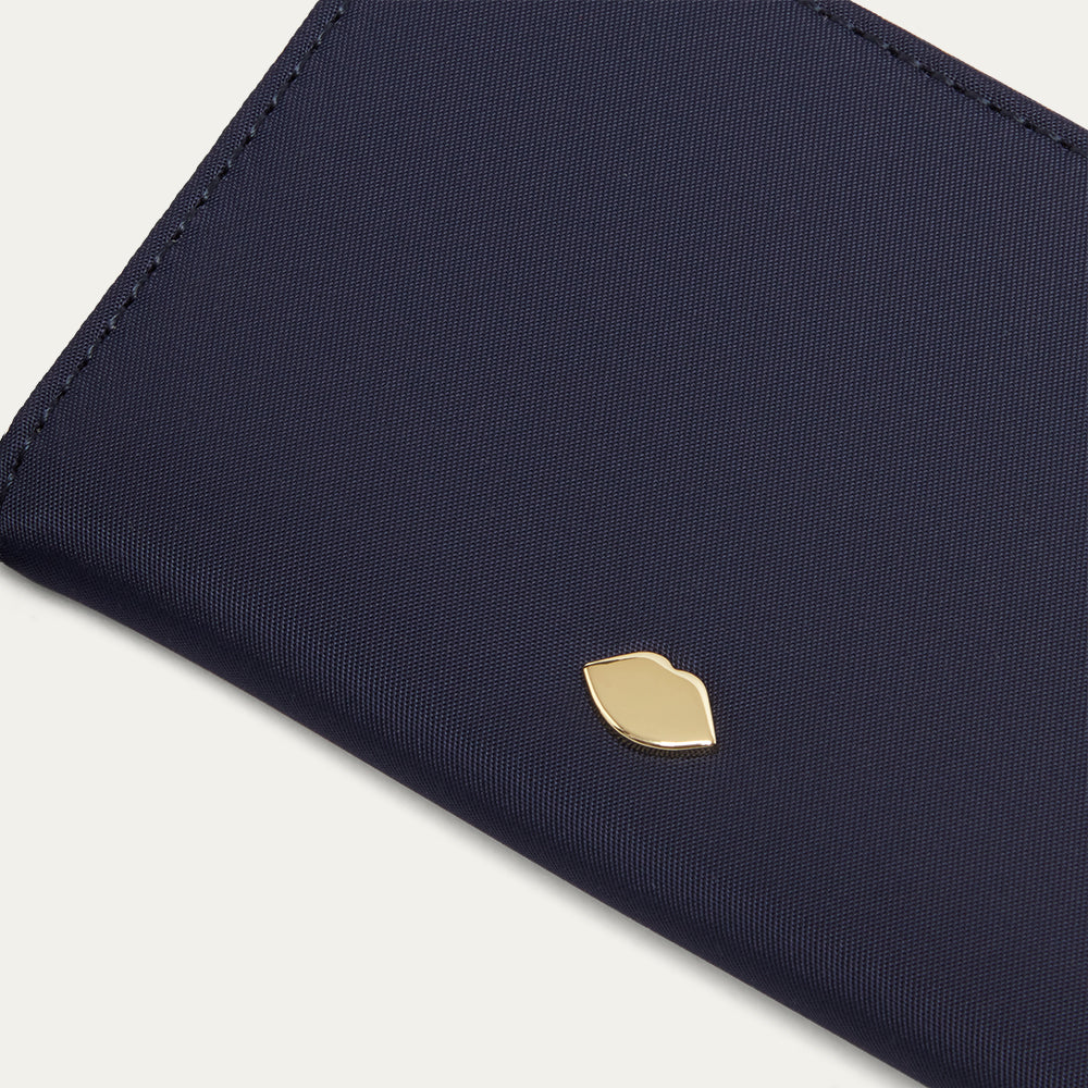 Navy blue wallet with a gold lip pin on a light gray background