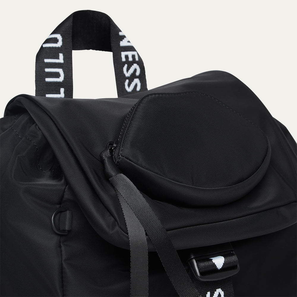 Black backpack with visible branding and a lip-shaped pocket on a light gray background