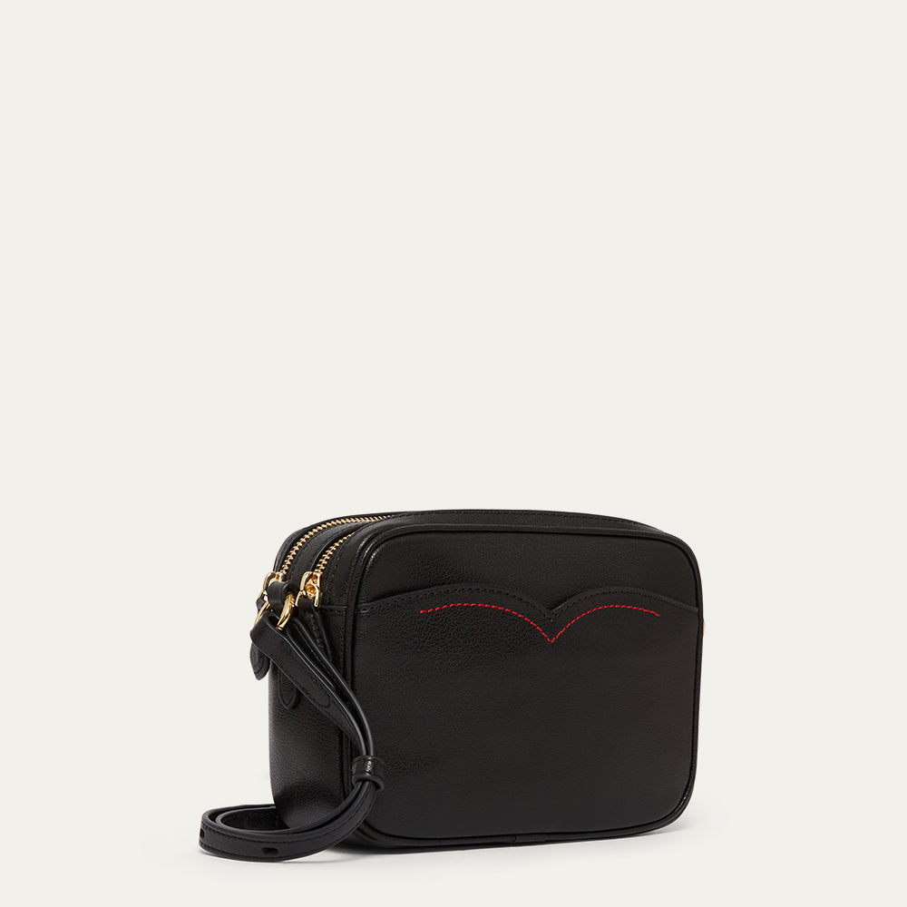 Black handbag with red stitching on a light gray background