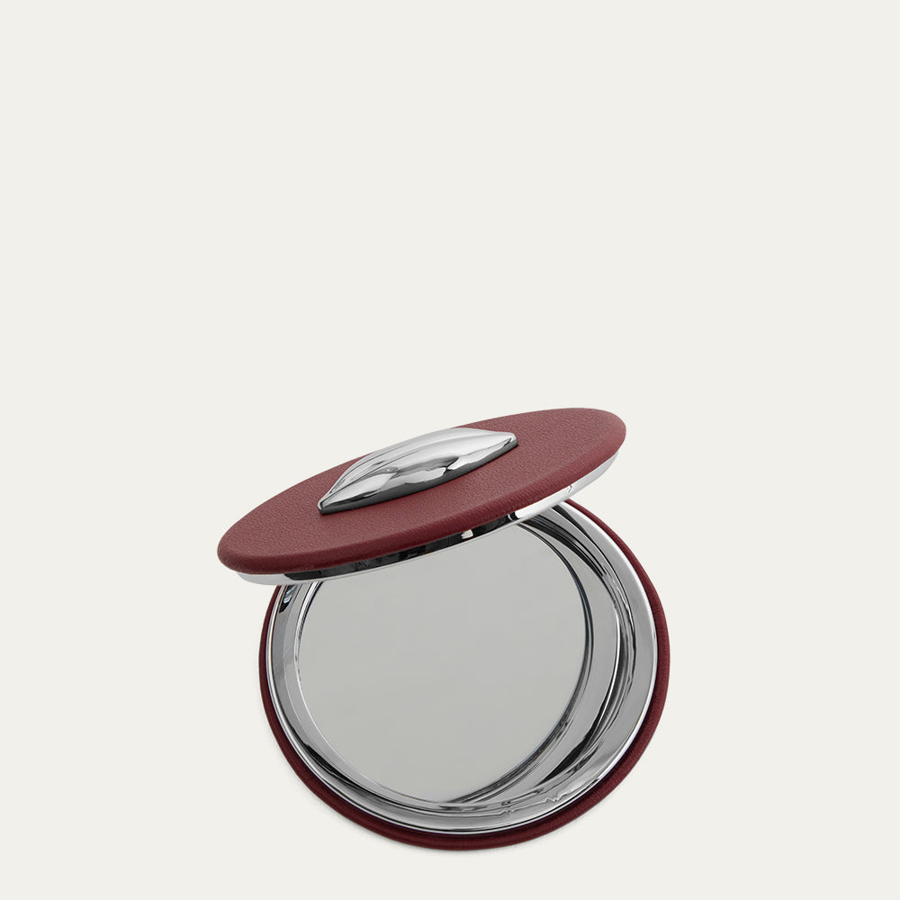 Compact mirror with a red lid on a white background