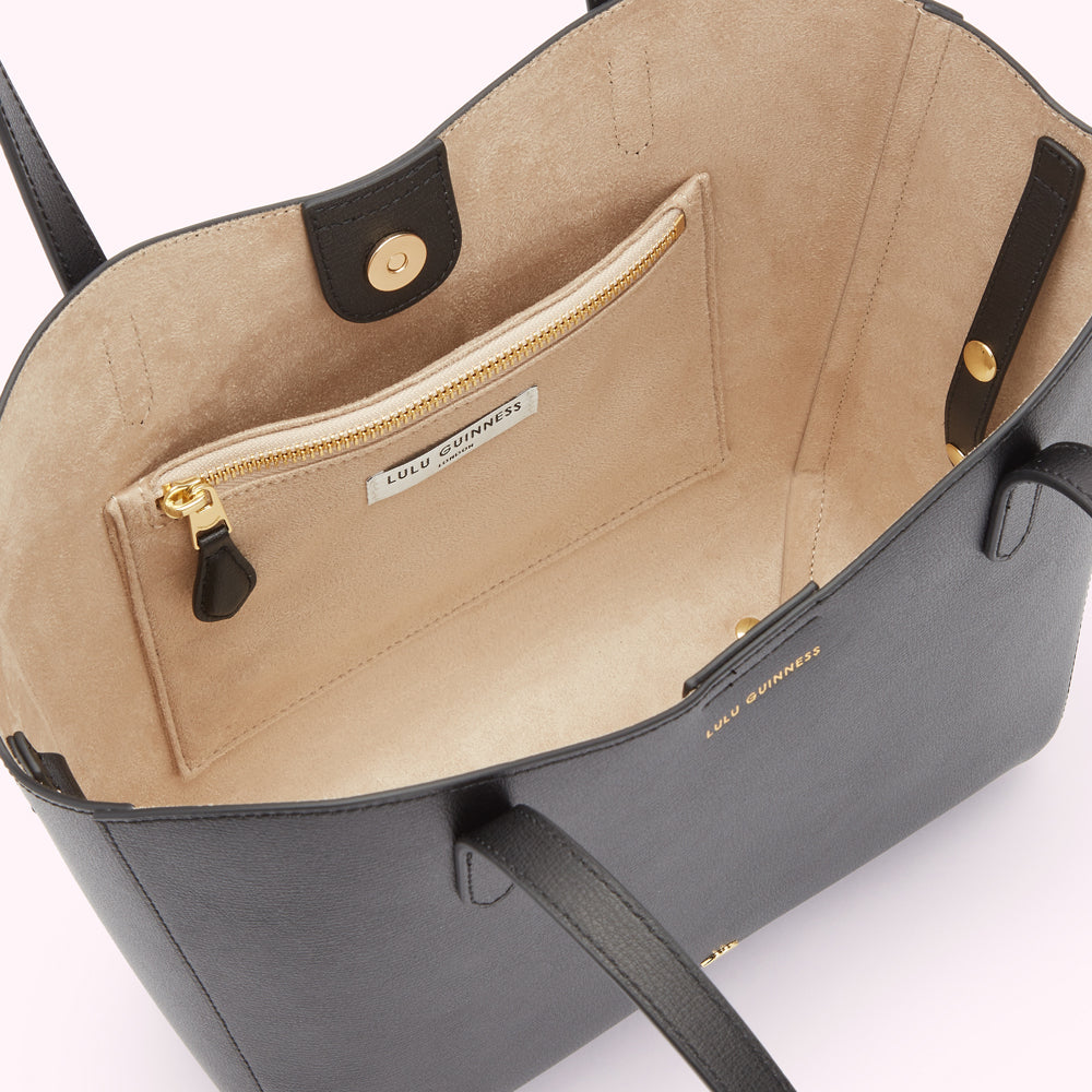 Inside image of a black leather tote bag showing the beige lining. Revealing the slip pocket and zip pocket inside and the magenetic closure.