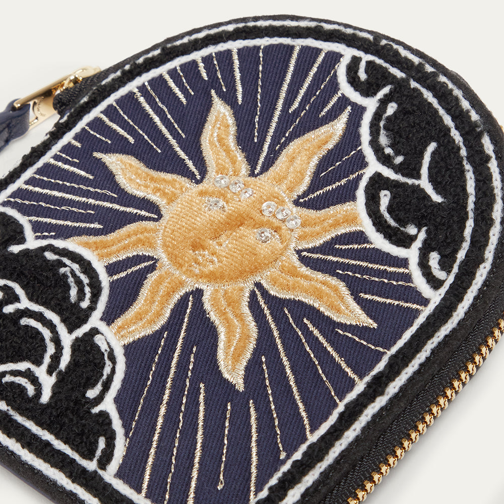 Embroidered coin purse with sun design on a dark blue background