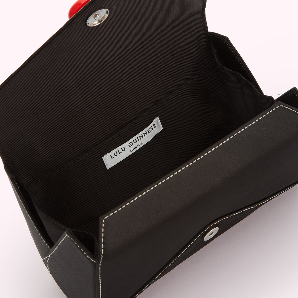 Open black Lulu Guinness London clutch with red clasp.