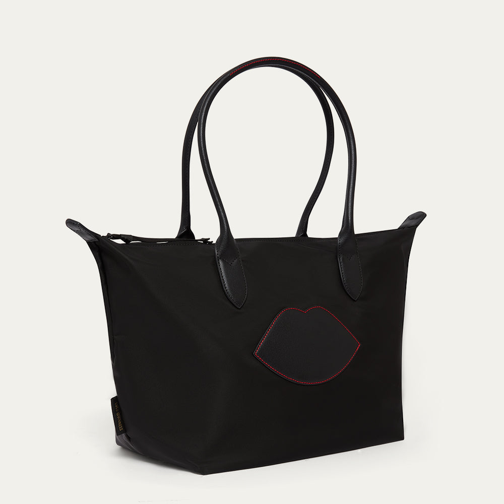 Black tote bag with red lip design on a light gray background