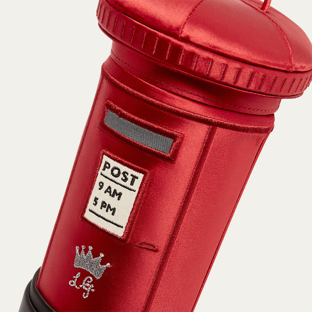 Red satin postlbox-shaped handbag with a post label on a white background