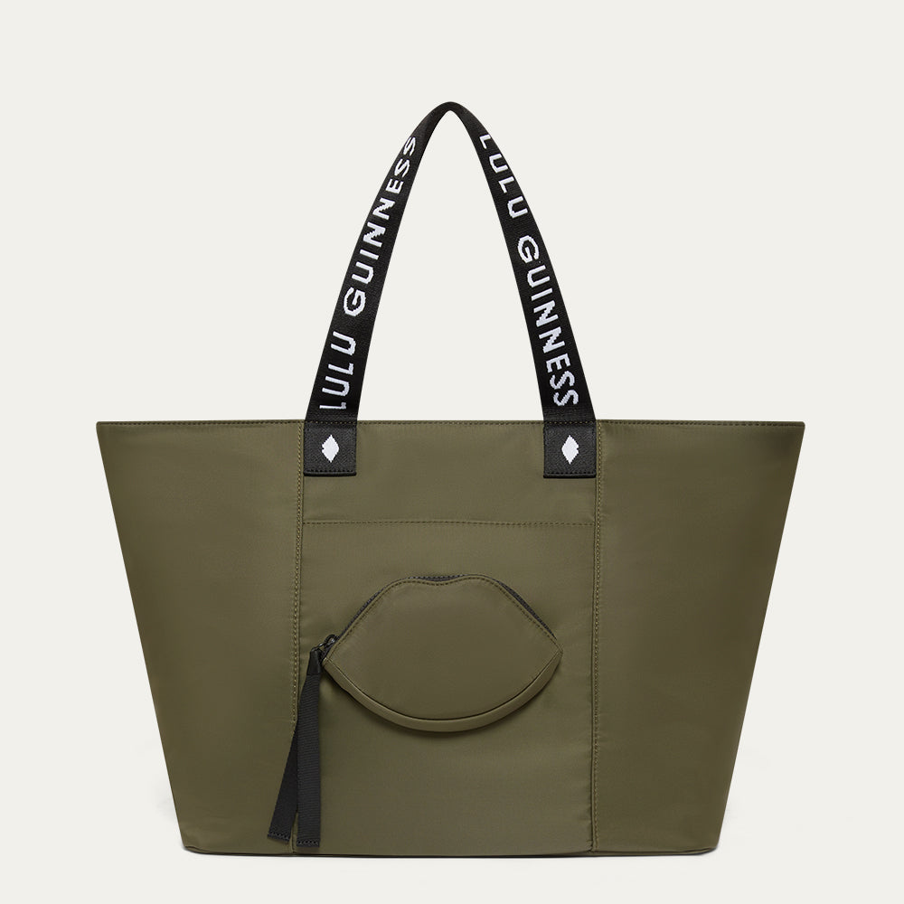 Green tote bag with Lulu Guinness straps and a lip shaped pocket on a light gray background