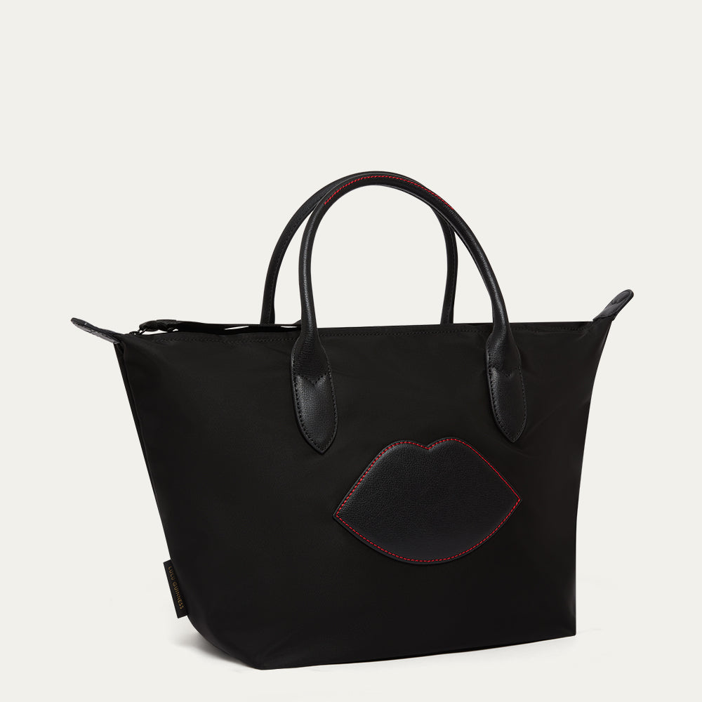 Black handbag with a lip-shaped patch on a light gray background