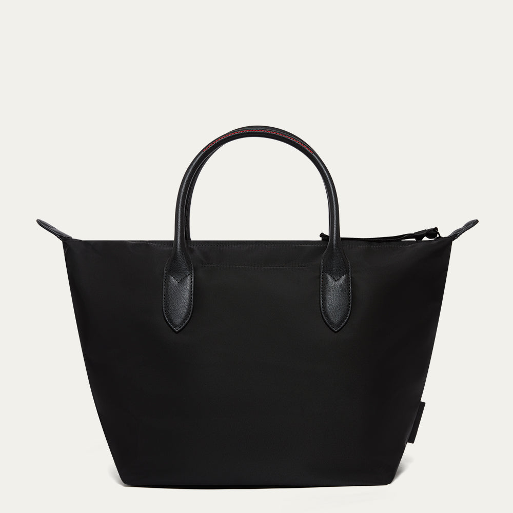 Black handbag with leather handles on a light gray background