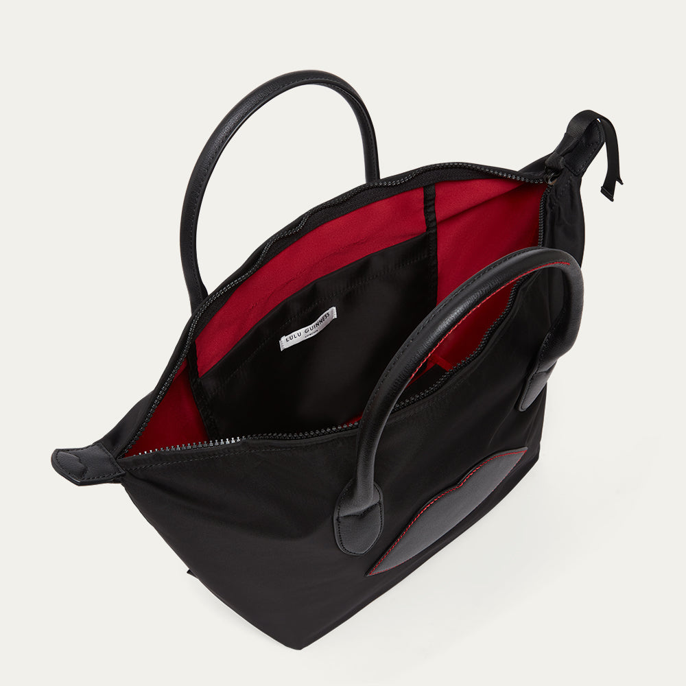 Black handbag with red interior on a light gray background