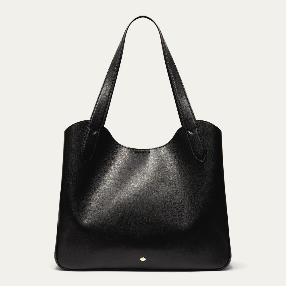 Black leather tote bag with gold lip accents on a light gray background