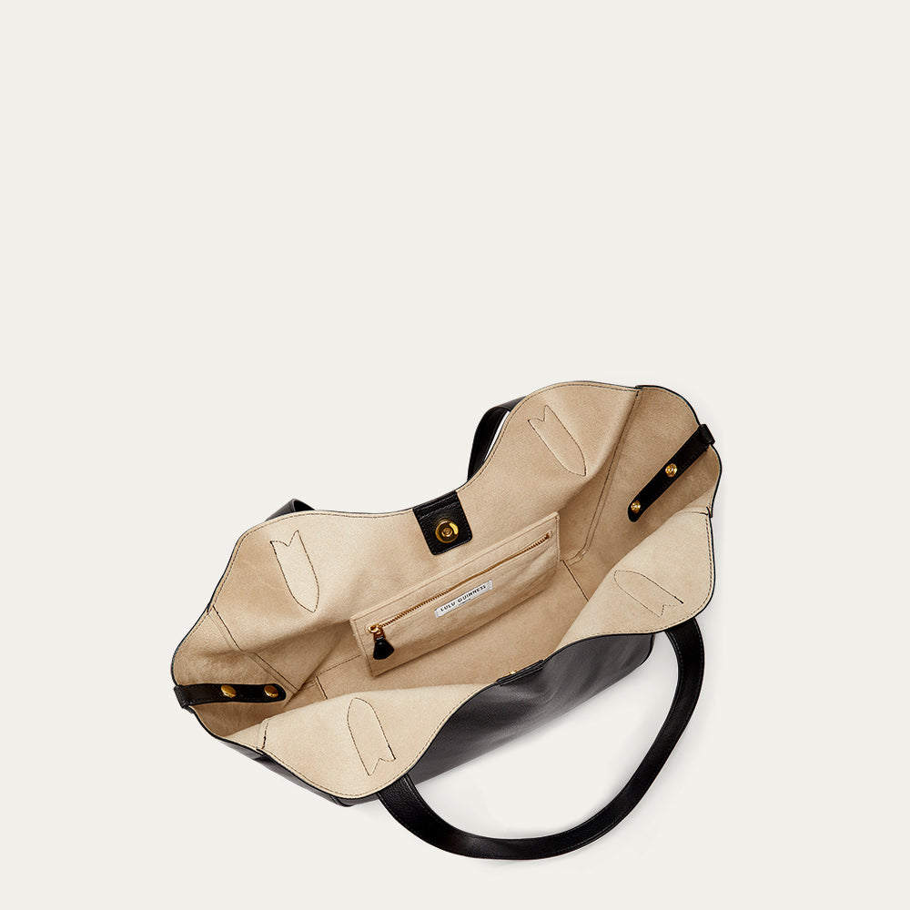 Inside of a black leather tote bag revealing the beige lining and inside pocket.