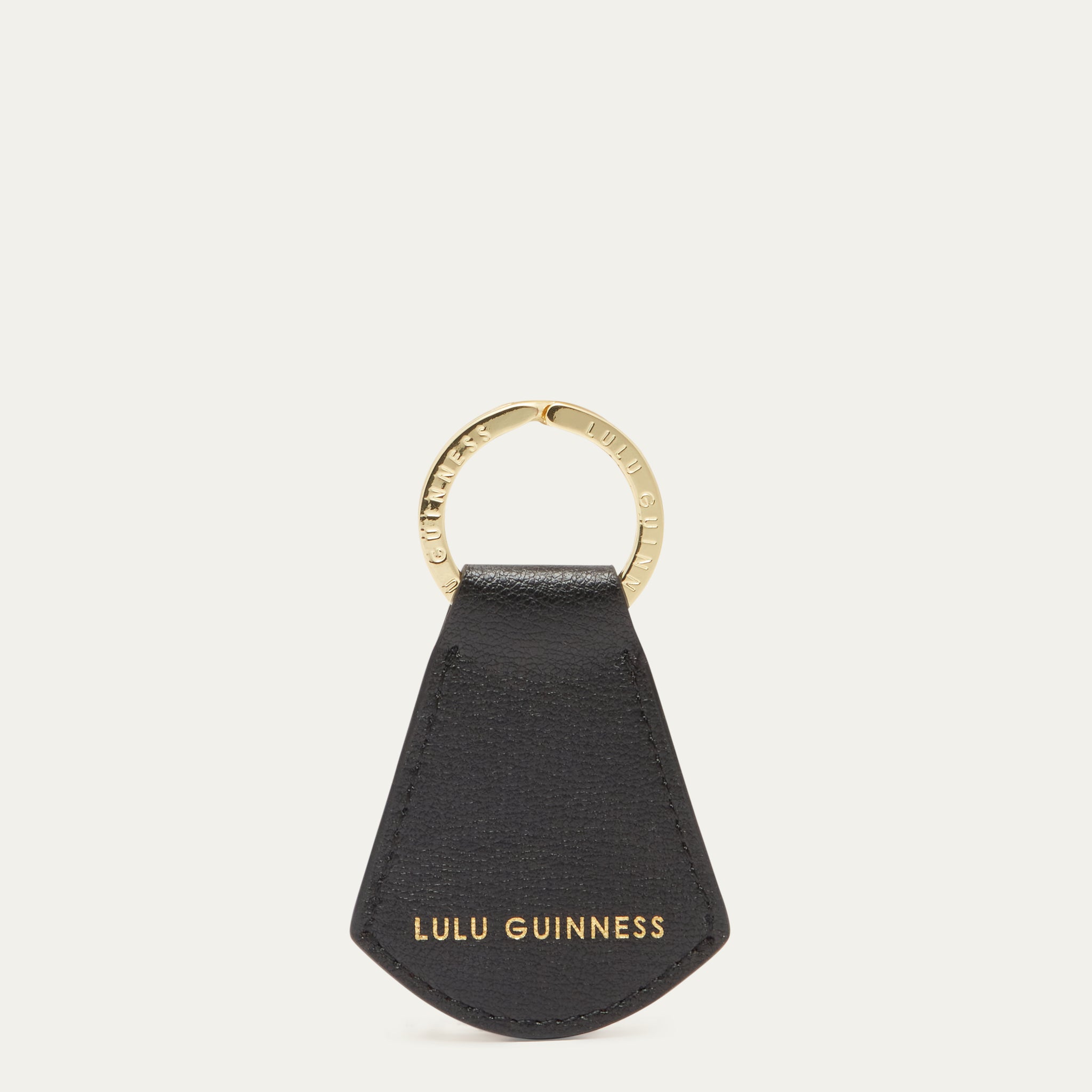 Black leather key fob with gold ring and 'Lulu Guinness' branding on a white background