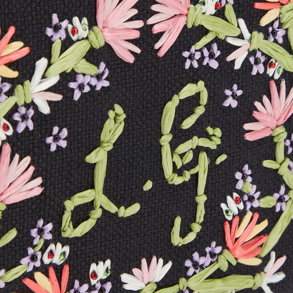 Close up image of pastel floral embroidred detail and L.G. embroidered monogram.