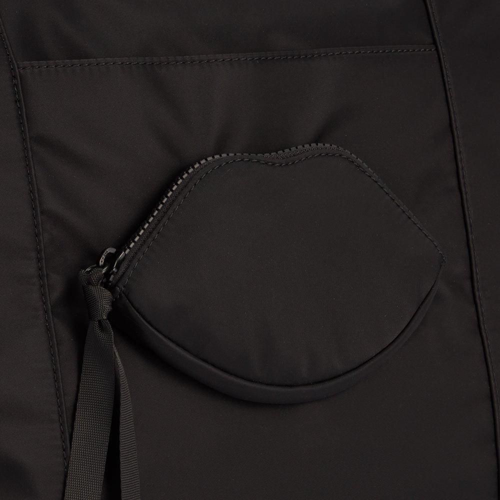 Close-up of a black bag with a lip-shaped zippered pocket.
