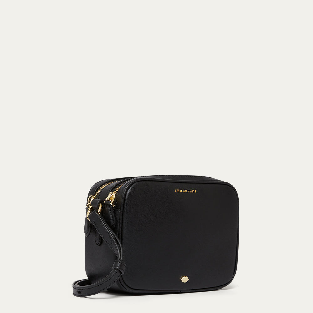 Black crossbody bag with gold accents on a light gray background