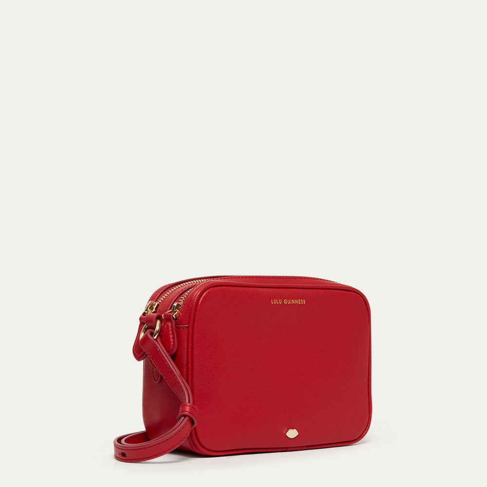Red crossbody bag with gold accents on a light gray background
