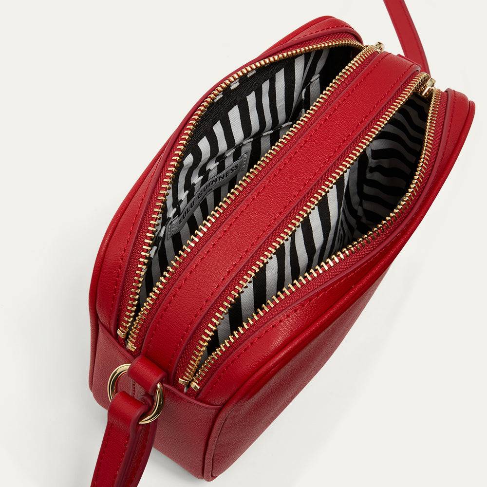 Red handbag with open with a black and white striped interior on a light gray background