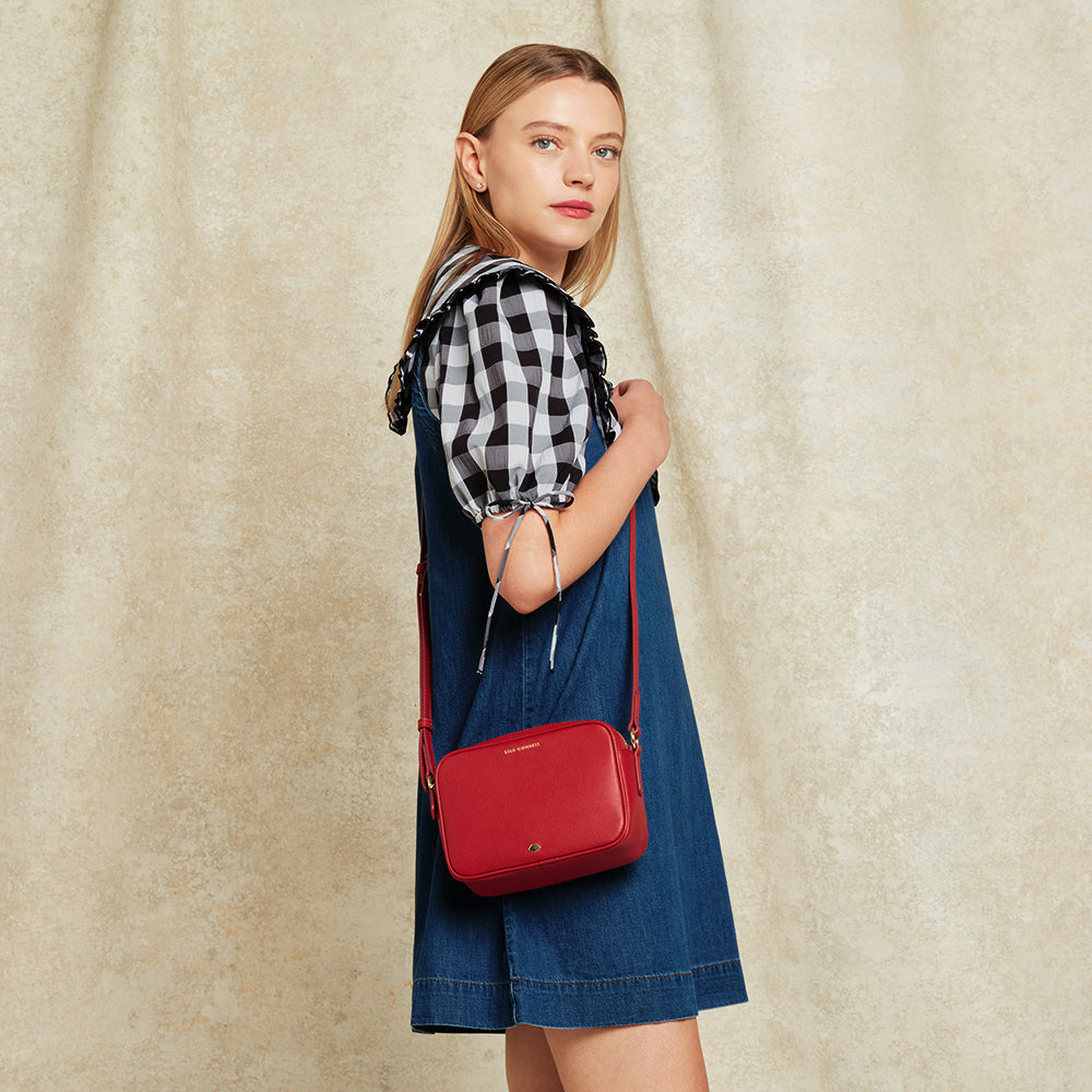 Woman holding a red handbag against a beige background