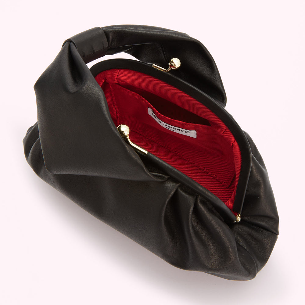 Black leather clutch purse with a red interior and gold clasp, open to reveal the Lucy Guinness label.
