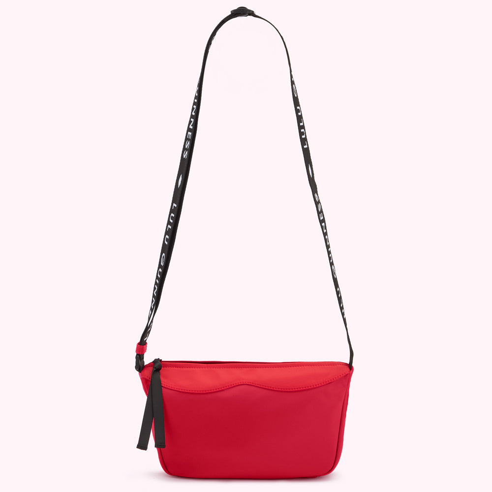 Red Lulu Guinness nylon crossbody bag with a black shoulder strap that says "Lulu Guinness."