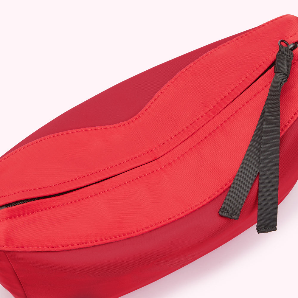 Close-up of a red nylon corssbody bag with black interior.