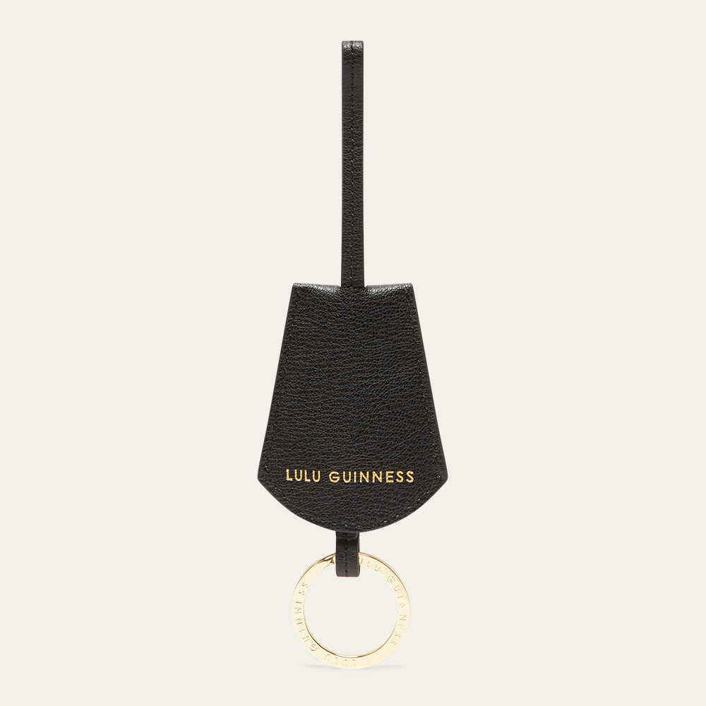 Black keychain with gold ring and 'Lulu Guinness' branding on a white background
