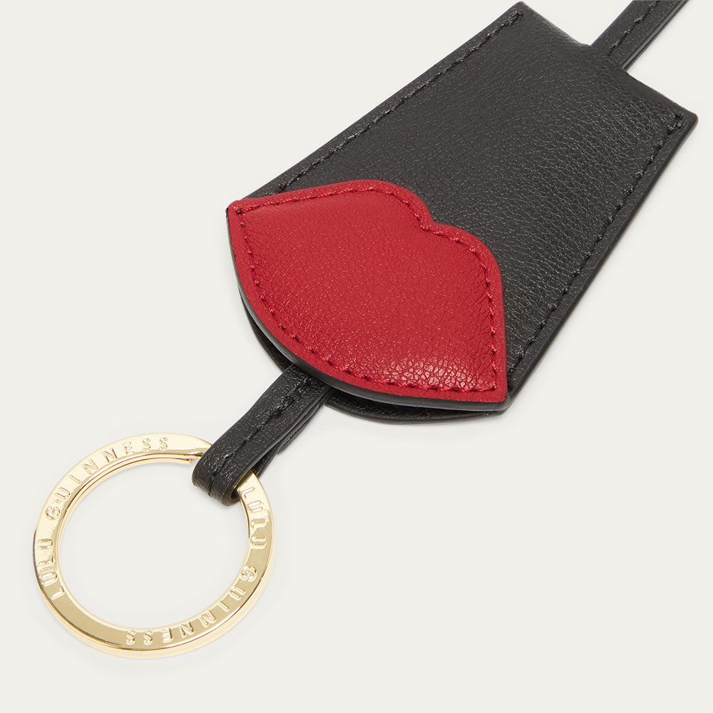 Black and red leather keychain with gold branded ring on a white background