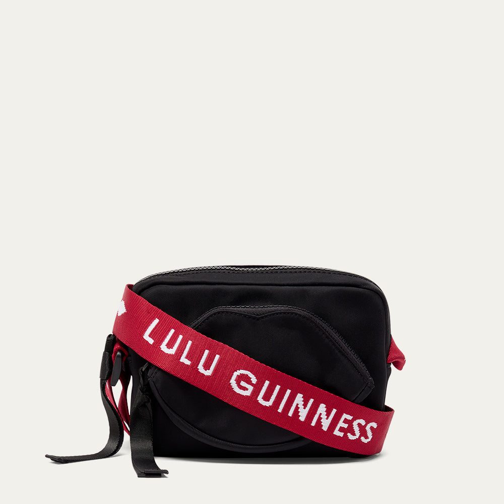 Black bag with a red strap featuring 'Lulu Guinness' on a light gray background
