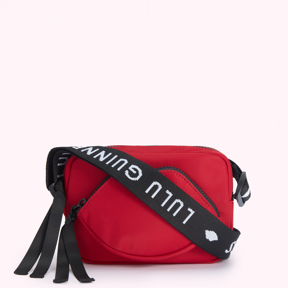 Red crossbody bag with a lip-shaped detail and a black strap with white "Lulu Guinness" lettering.