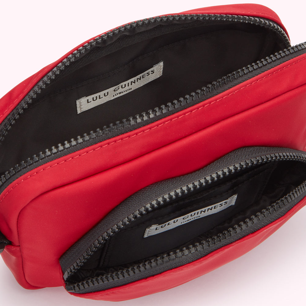 Red Lulu Guinness crossbody bag open to show the interior compartments and branding label.