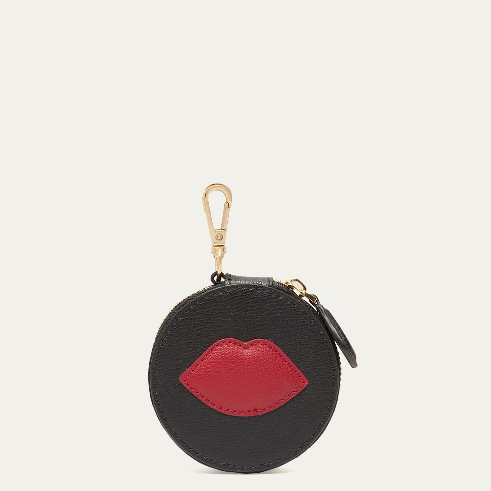 Black round coin purse charm with red lips design on a beige background