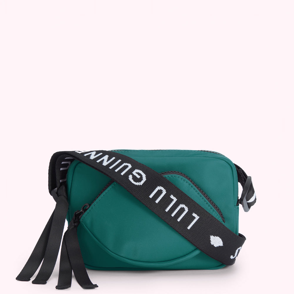 Green Lulu Guinness crossbody bag with a lip-shaped front pocket and black strap with white logo.
