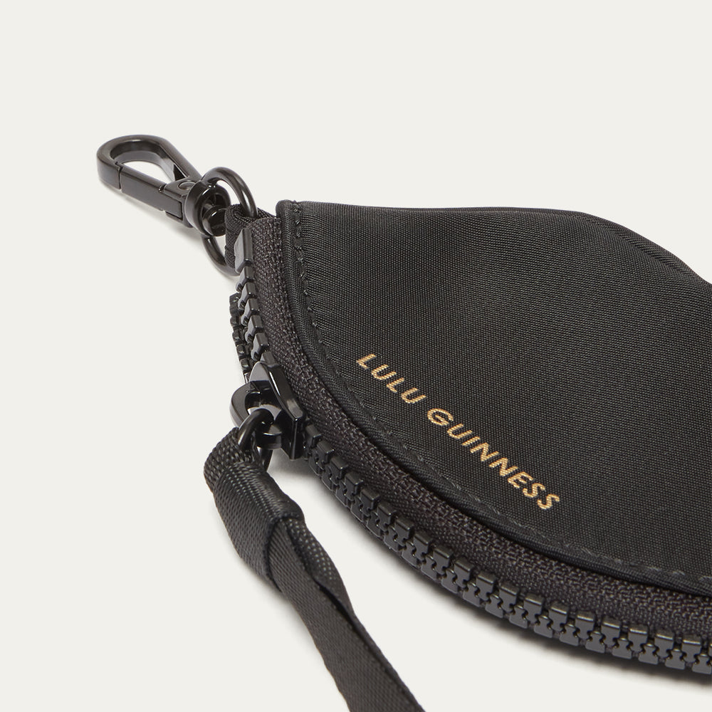 Black keychain pouch with 'Lulu Guinness' branding on a light gray 