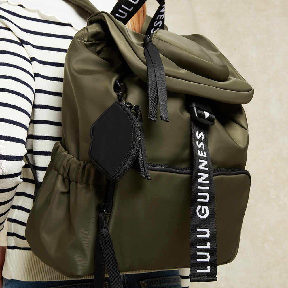 Black nylon lip sharped charm clipped on a green backpack. 