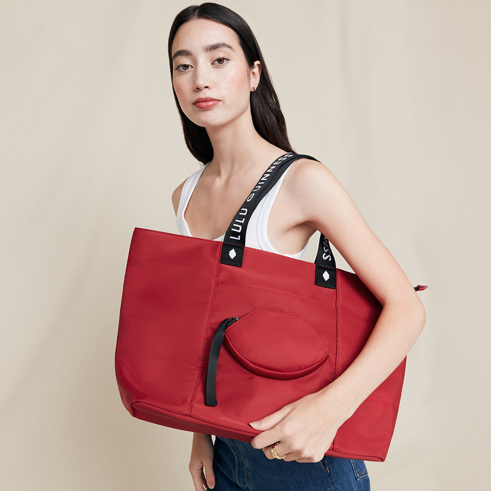 Woman holding a red tote bag with a beige background