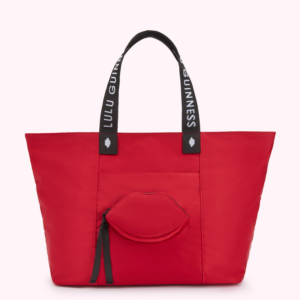 Red tote bag with "Lulu Guinness" on straps and a lip-shaped pocket.