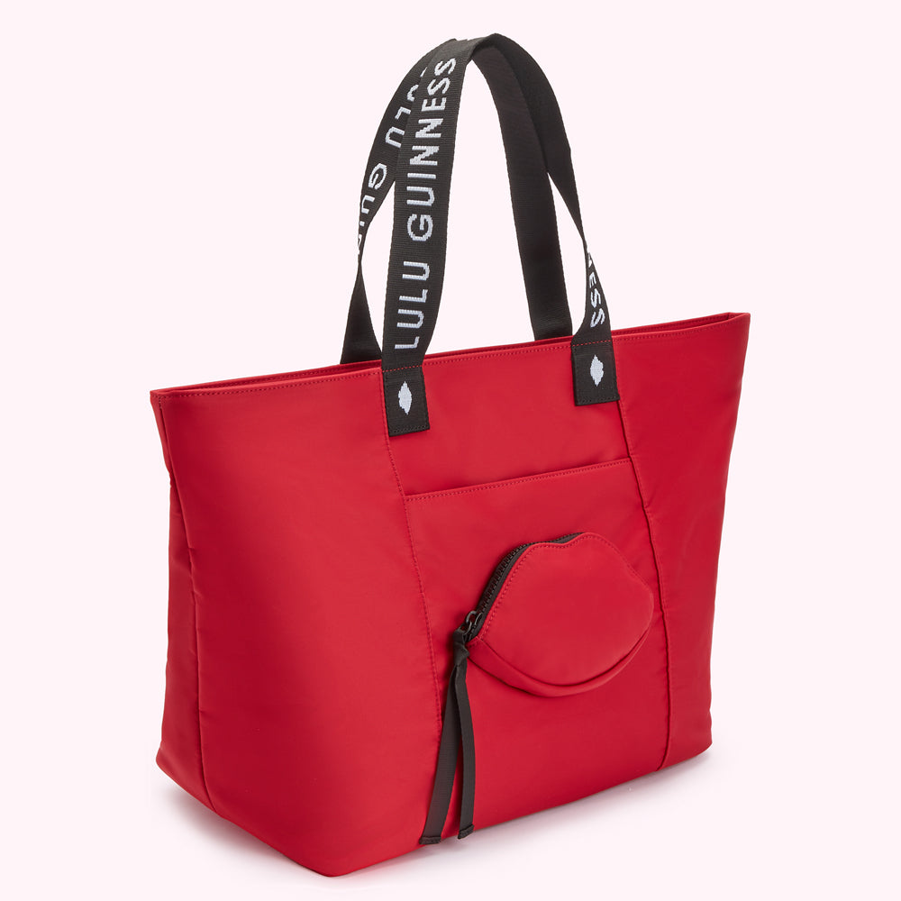 Red tote bag with "Lulu Guinness" on straps and a lip-shaped pocket.