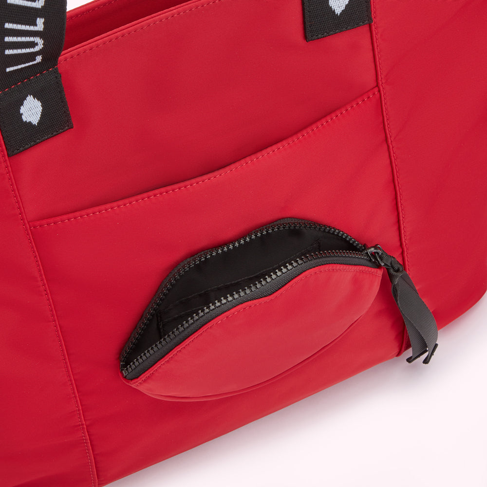 Close-up of a red bag with a lip-shaped zippered pocket.