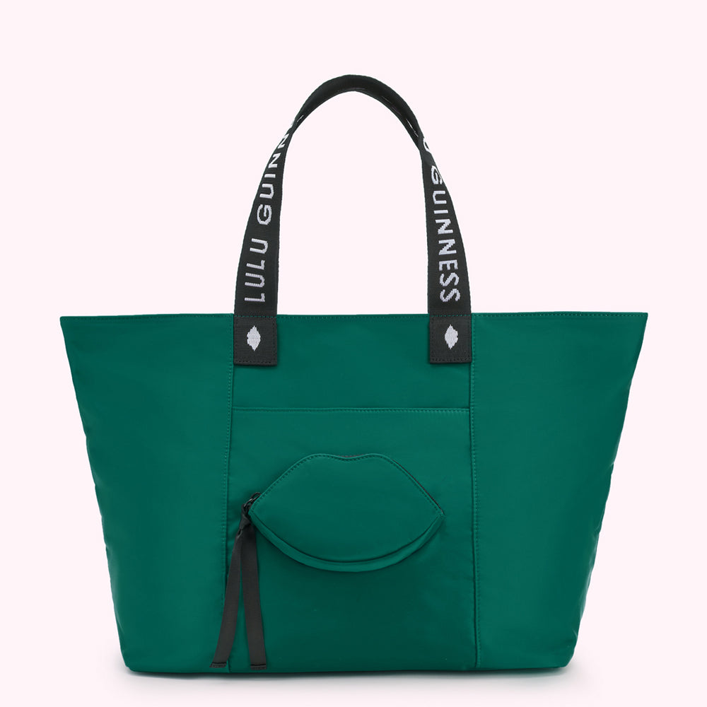 Green tote bag with "Lulu Guinness" on straps and a lip-shaped pocket.