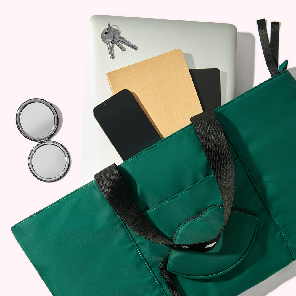 A green nylon tote bag handbag with a laptop, notebooks, smartphone, keys and compact mirror spilling out