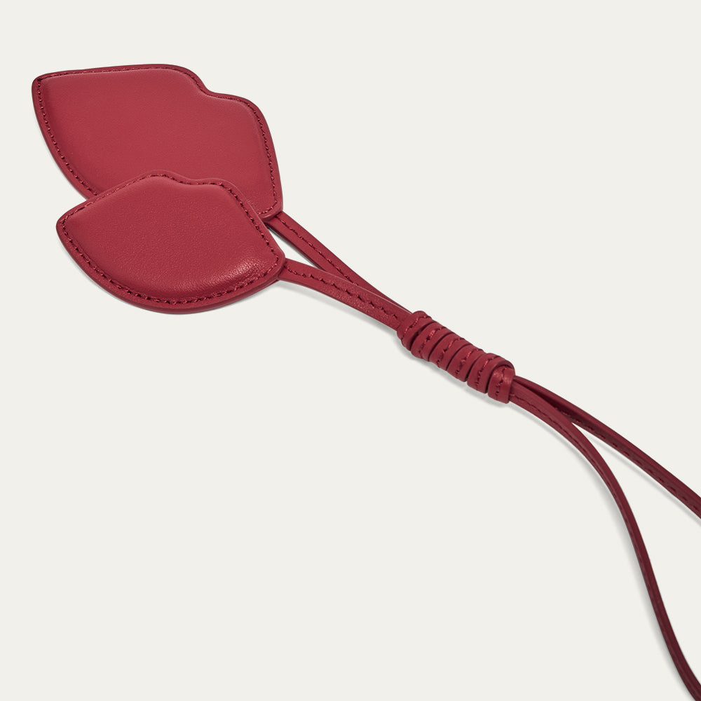 Red leather lip shaped charm on a light gray background