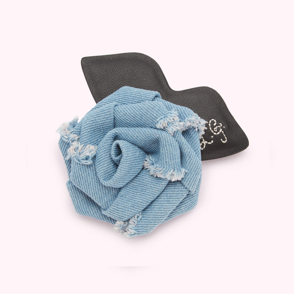 Light blue denim rose brooch with a black leather accent.
