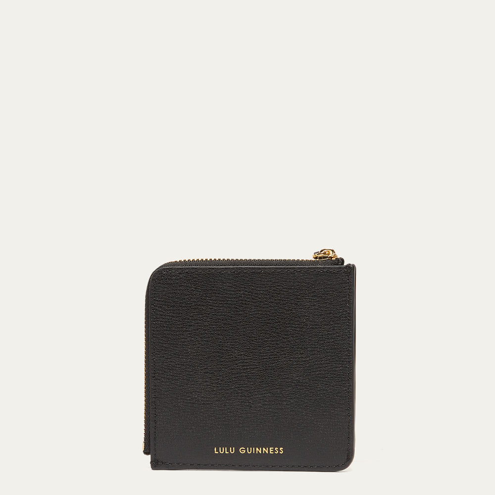 Black wallet with gold zipper and 'Lulu Guinness' branding on a light gray background