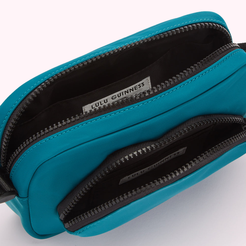 Teal Lulu Guinness crossbody bag open to show interior compartments and brand label.
